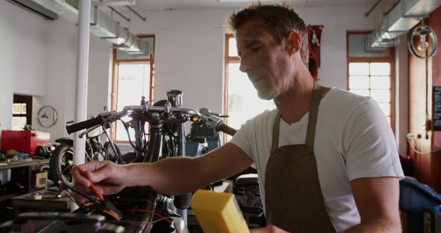 Caucasian male mechanic fixing motor bike in workshop, unaltered. Motorbike mechanics, small business, work, labor and working concept.