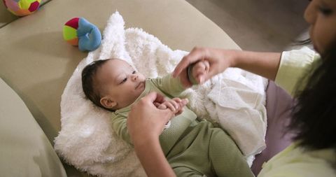 Mother bonding with baby girl on soft white blanket