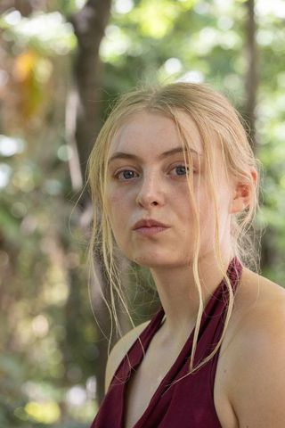 Sunlit blonde woman reflecting in woodland closeup portrait wearing maroon halter top