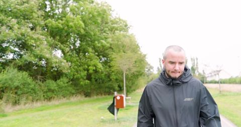Man jogging in park amidst greenery in black jacket
