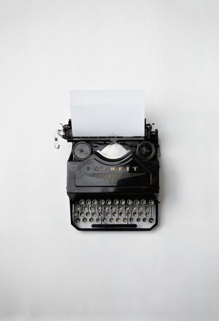 This image shows a vintage black typewriter with a blank paper sheet on a white background. It is perfect for representing writing, nostalgia, and the concept of old-fashioned communication. Use this for blog posts about the history of writing, retro-themed designs, or articles related to writing and creativity.