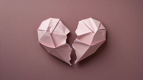 Torn origami heart halves on mauve background