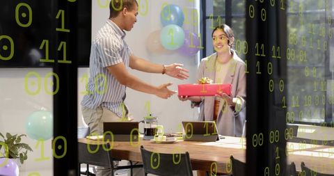 Colleagues exchanging gift during office celebration, balloons and binary code overlay