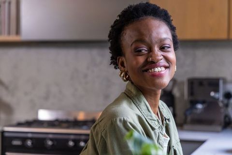 African american woman smiling in modern kitchen with espresso machine and countertop