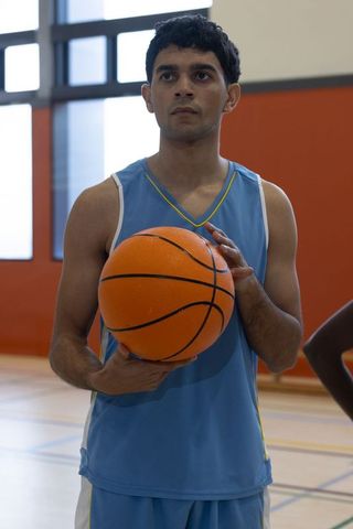 Basketball Athlete Holding Ball on Indoor Court Wearing Blue Sportswear