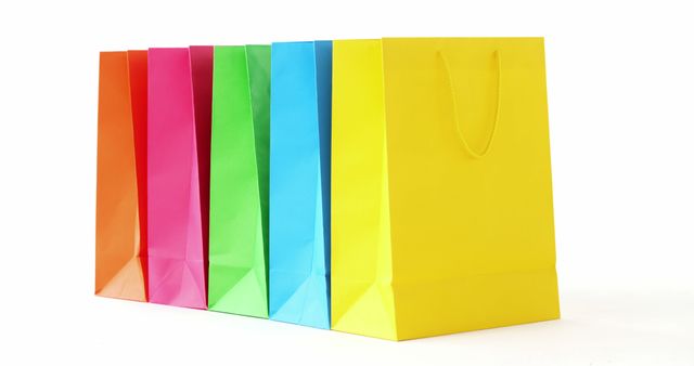 Bright and colorful shopping bags lined up against a white background, creating a vibrant and visually appealing scene. Perfect for illustrating retail shopping, consumerism, or promotional materials for sales events. Effective as an attention-grabbing image in marketing campaigns for stores, boutiques, or online businesses highlighting special offers or new collections.