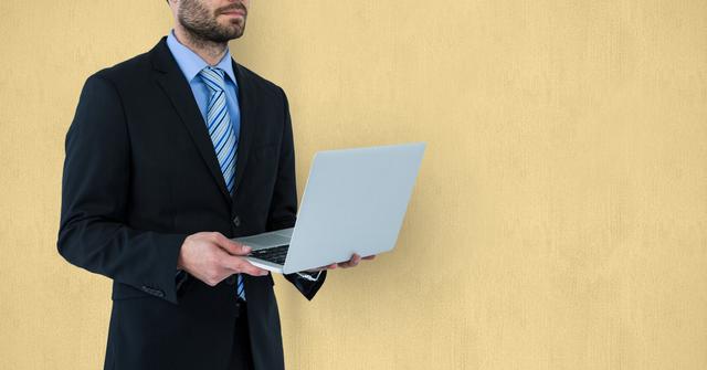 Professional Businessman Holding Laptop Against Yellow Background - Download Free Stock Photos Pikwizard.com
