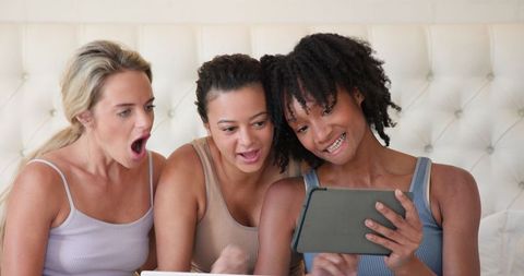 Diverse Female Friends Bonding Over Tablet in Cozy Interior