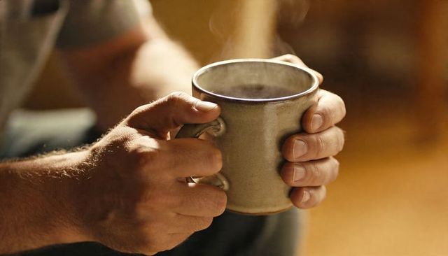 Cradling steaming ceramic mug in hands closeup cozy morning ritual warming hands