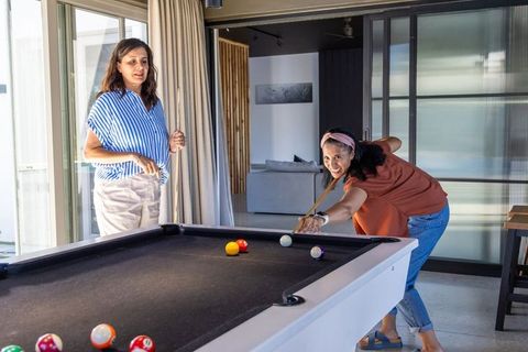 Diverse women playing pool in modern home recreation room enjoying friendly billiards match