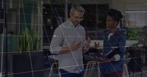 Coworkers analyzing data on digital grid in modern office