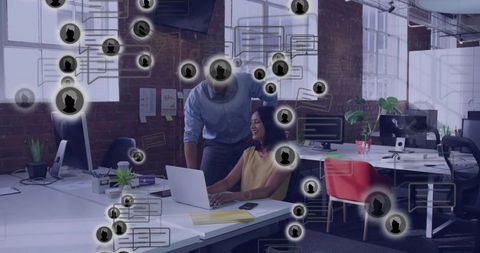 Coworkers collaborating at laptop with virtual communication overlays in open-plan office
