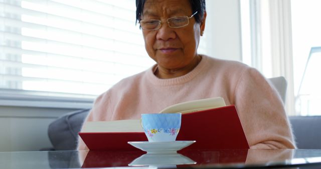 Senior Woman Reading Book with Teacup on Table - Download Free Stock Images Pikwizard.com