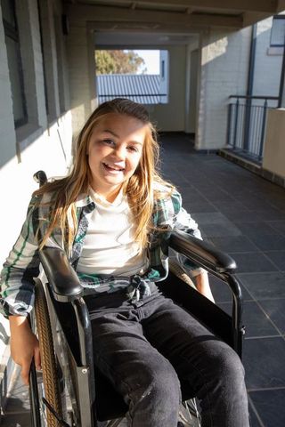 Smiling Young Girl in Wheelchair Enjoys Sunny Day Outdoors