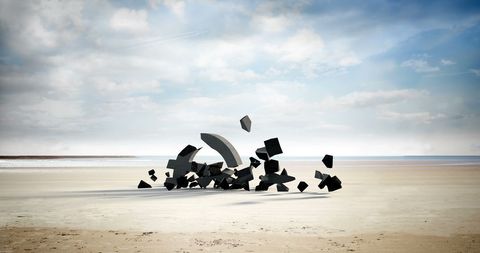 Shattered stone letters on sandy beach under vast sky vivid scene