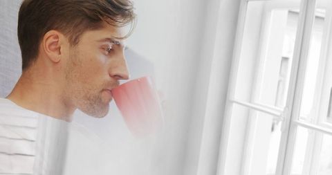 Serene morning moment: man enjoying beverage by window