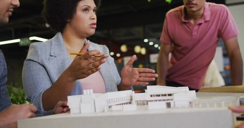 Design team presenting architectural model in modern office, woman leading project review