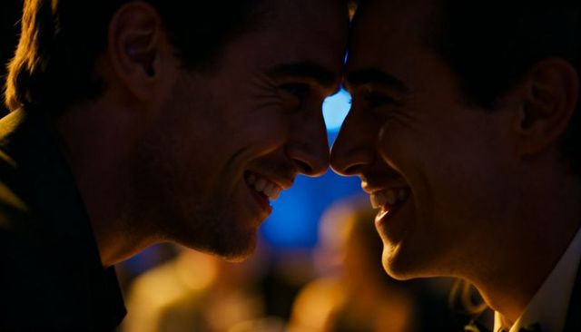 Romantic gay couple sharing intimate forehead touch at wedding reception warm bokeh lighting