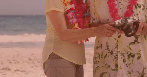 Senior Couple Enjoying Beach Vacation with Vintage Camera