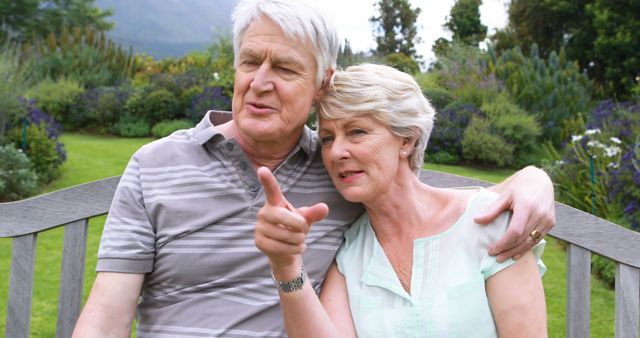 Senior Couple Relaxing on Bench in Garden, Man Pointing - Download Free Stock Images Pikwizard.com