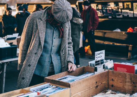 Man searching for vinyl records and book at outdoor market in winter attire