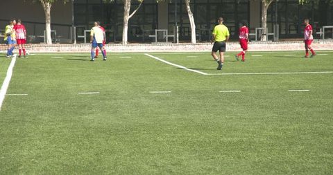 Football referee signaling during match with players in action