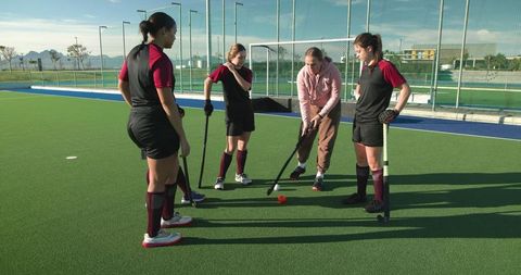 Female Coach Guides Teen Hockey Players on Field Techniques