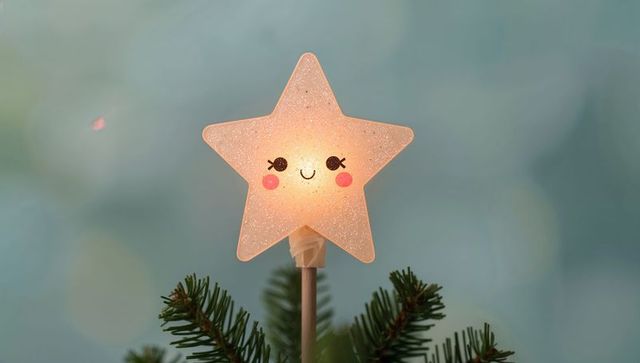 Glowing smiling star tree topper casting warm yellow light on fir branch with glitter