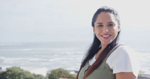 Smiling Woman Standing on Balcony Overlooking Ocean