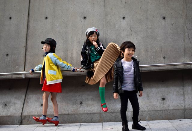 Three children are displaying their unique fashion sense while enjoying themselves in a contemporary urban environment. Ideal for advertising children's fashion, modern family life, youth culture, or urban lifestyle.