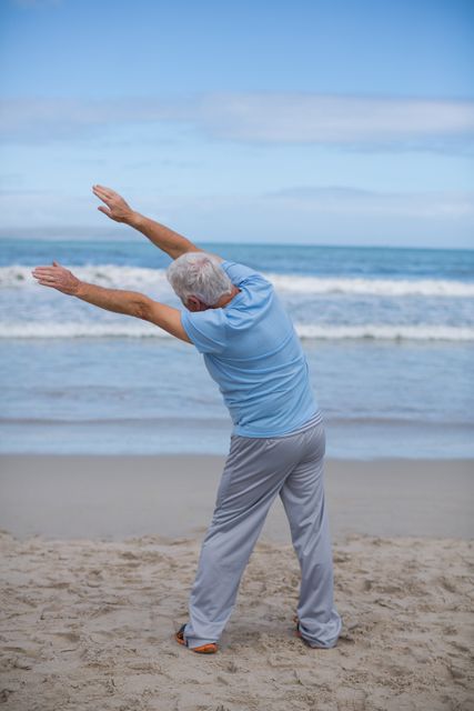 Senior man stretching on beach, promoting active and healthy lifestyle for elderly. Ideal for use in wellness, fitness, and retirement lifestyle content. Perfect for illustrating outdoor physical activities and health routines for seniors.