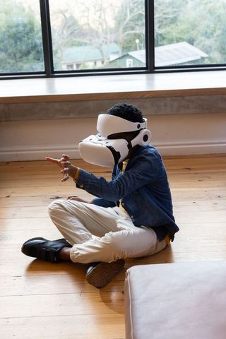 African american boy exploring virtual reality wearing white vr headset on wooden floor