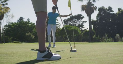 Women playing golf wearing masks on sunny day