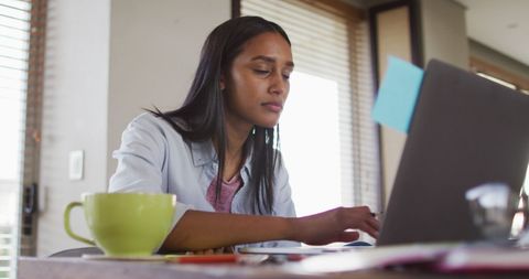 Focused Woman Remote Working on Laptop at Cozy Home Desk