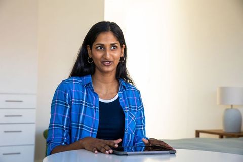 Indian woman using tablet in modern minimalistic interior