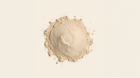 Fine beige milk powder mound against neutral background