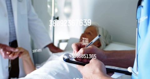 Elderly patient monitoring bedside with nurse charting on tablet and doctor holding wrist