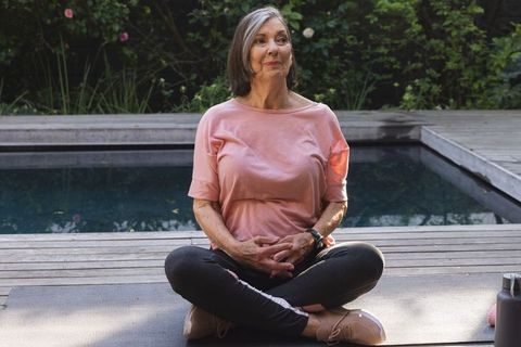 Senior Woman Practicing Yoga by Pool in Outdoor Setting