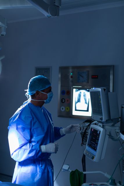Side view of male surgeon looking at monitor in operating room at hospital