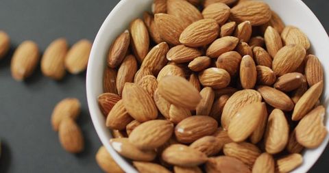 Nutrient-rich almonds overflown bowl on gray surface