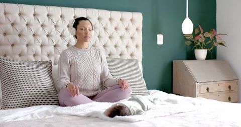 Asian Mother Meditating with Baby on Bed in Serene Home Setting