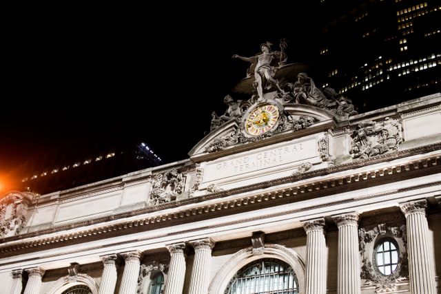 Grand Central Terminal exterior illuminated in night lights showcasing classical architecture and iconic clock in New York City. Ideal for travel brochures, historical features, Manhattan cityscapes, architectural studies, urban tourism promotions, and New York City postcards.