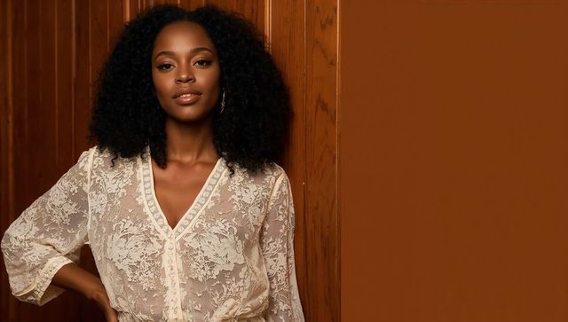 Elegantly posing woman in sheer lace blouse by wooden wall