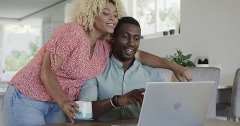 Happy couple using laptop together in living room