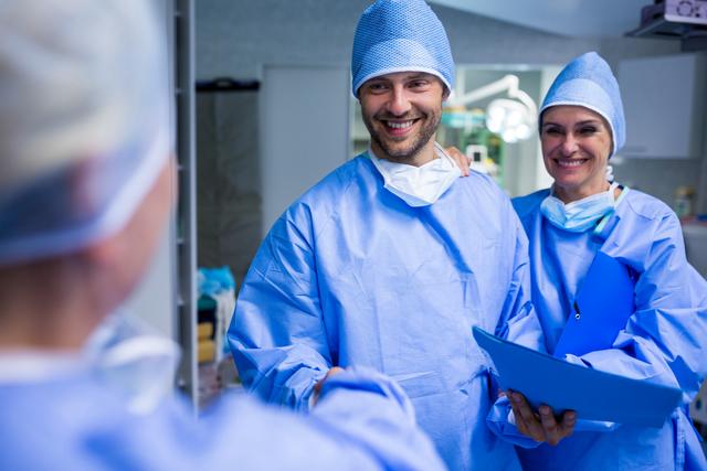 Surgeons in blue scrubs and surgical caps shaking hands in an operating room, symbolizing teamwork and collaboration in a hospital setting. This image can be used for healthcare promotions, medical teamwork concepts, hospital advertisements, and articles about surgical procedures.