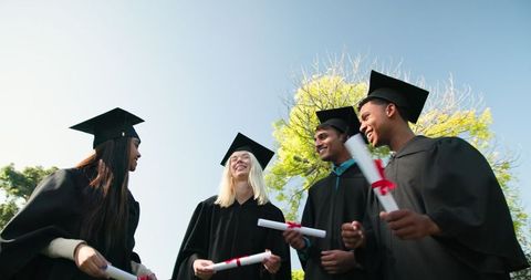 Diverse Graduates Celebrating with Diplomas Outdoors on Sunny Day
