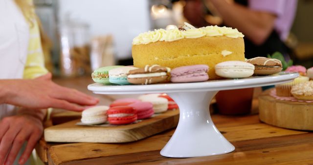 Bright, appetizing shot featuring a variety of macarons surrounding a delicious-looking cake. Ideal for use in advertisements, blogs, or websites related to baking, patisseries, and dessert recipes. Can be used to evoke feelings of indulgence and sweetness, perfect for social media posts and promotional material.