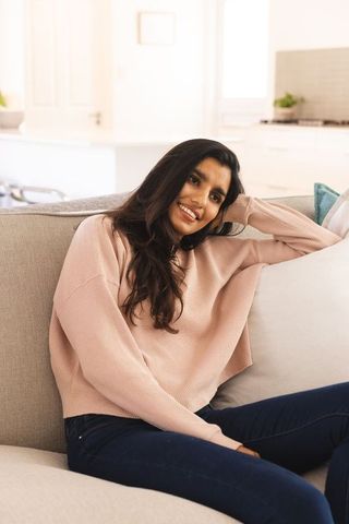 South asian woman relaxing on sofa in cozy minimalist home