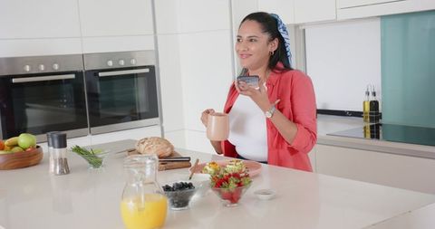Woman in modern kitchen conversing on smartphone while preparing meal