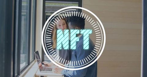 Young professionals collaborating on laptop with nft digital overlay in bright office